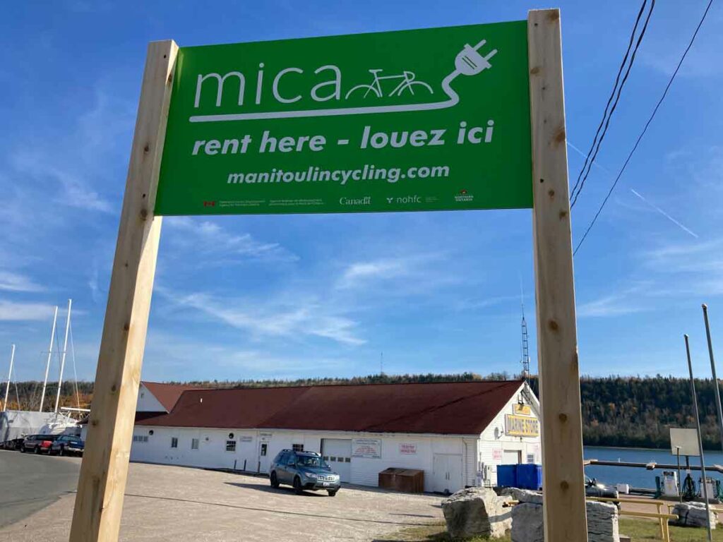 Look for the signs: MICA e-bike rental locations (listed on the MICA website) are found near bright green signs like this one at 
the Gore Bay Marina. Photo by Isobel Harry.