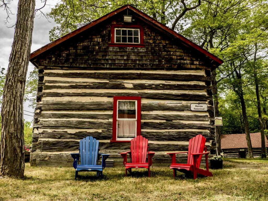 The lush grounds of the Centennial Museum of Sheguiandah are dotted with log cabin mini-museums. Manitoulin chairs and picnic tables welcome visitors to soak up the history. Photo by Isobel Harry.