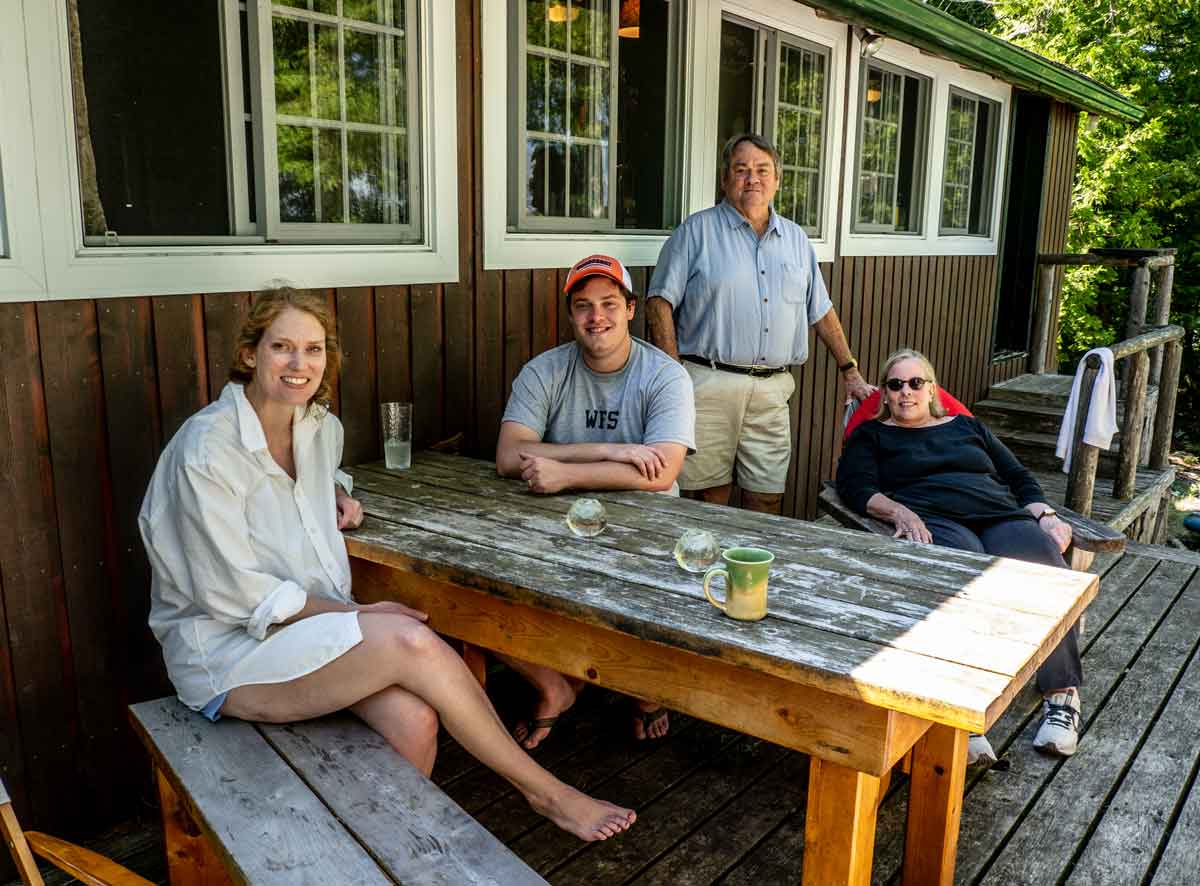 The Ward family at their cabin on Lake Manitou: John Ward IV (standing, right) and his wife Phyllis return every summer. Daughter Elizabeth is seated at picnic table with son-in-law Charles; missing from photo is baby Jane, the fifth generation of Wards to vacation here, as she was down for a nap. Photo by Isobel Harry.